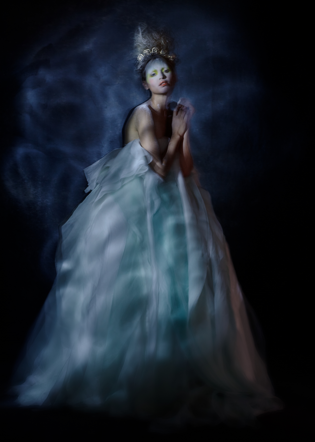 A figure in a dark fashion portrait lit by a controlled beam of light.