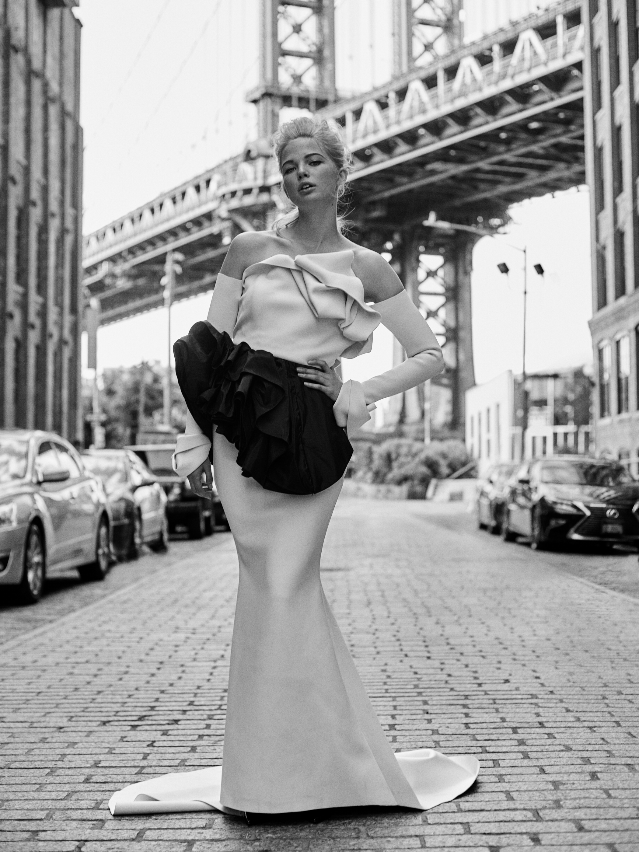 A model in a couture gown posed against a New York street wall.