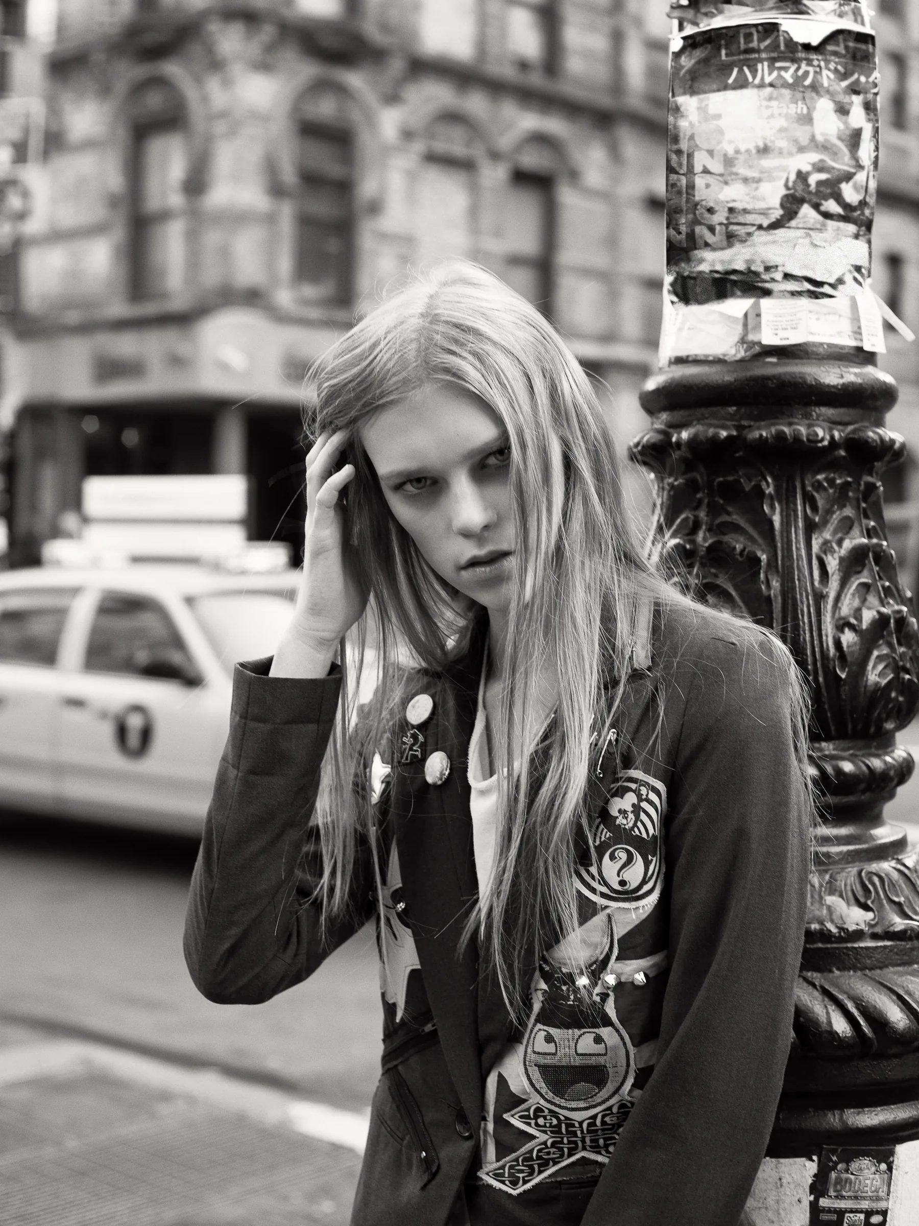 A woman in a decorated black jacket pauses beside a stone monument in New York.