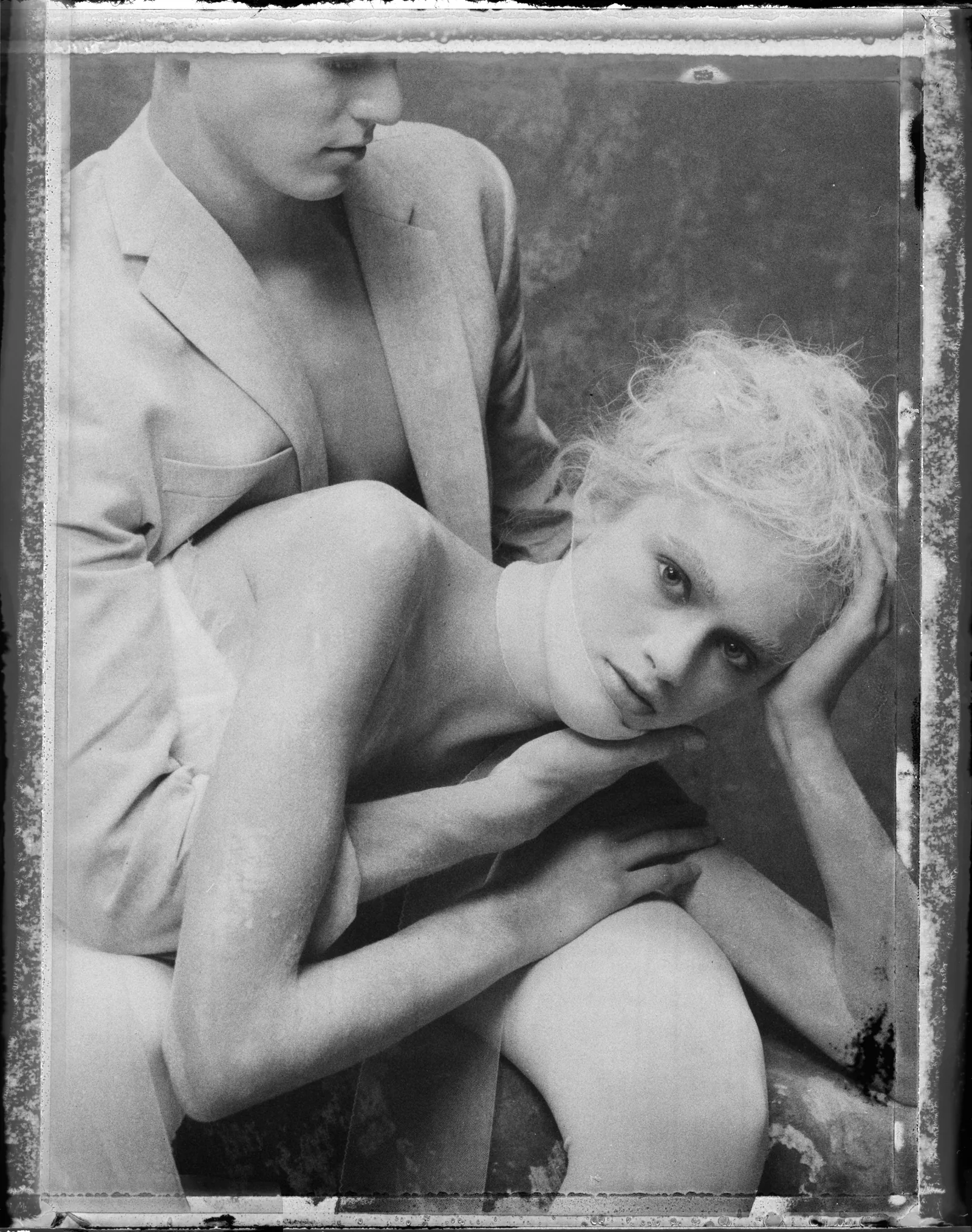 Two figures gather inside the distressed border of a monochrome photographic print.