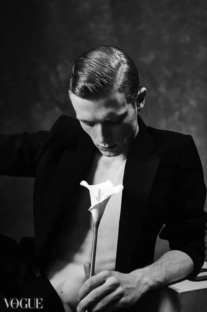A formal profile portrait with a calla lily against darkness.